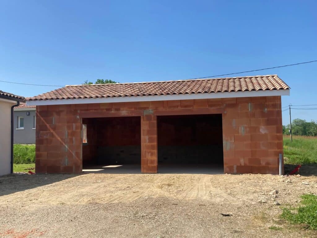 Construction garage double en briques et toit tuiles Garage double en briques rouges (gros œuvre) avec toit en tuiles terre cuite, prêt à recevoir les portes.