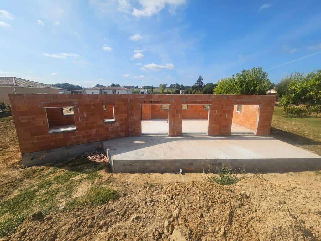 Construction maison : Murs en Bbio'bric sur fondation béton Murs de briques Bbio'bric d'une maison en construction. Fondation sur dalle béton, ouvertures prêtes. Ciel bleu éclatant.