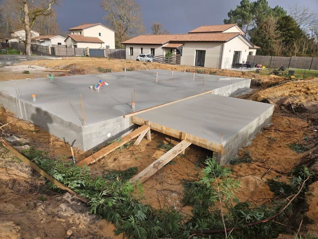 Fondation dalle béton pour maison neuve et vide sanitaire Fondation en dalle béton pour maison neuve. La structure surélevée présente des attentes de plomberie et d'armature sur le chantier.
